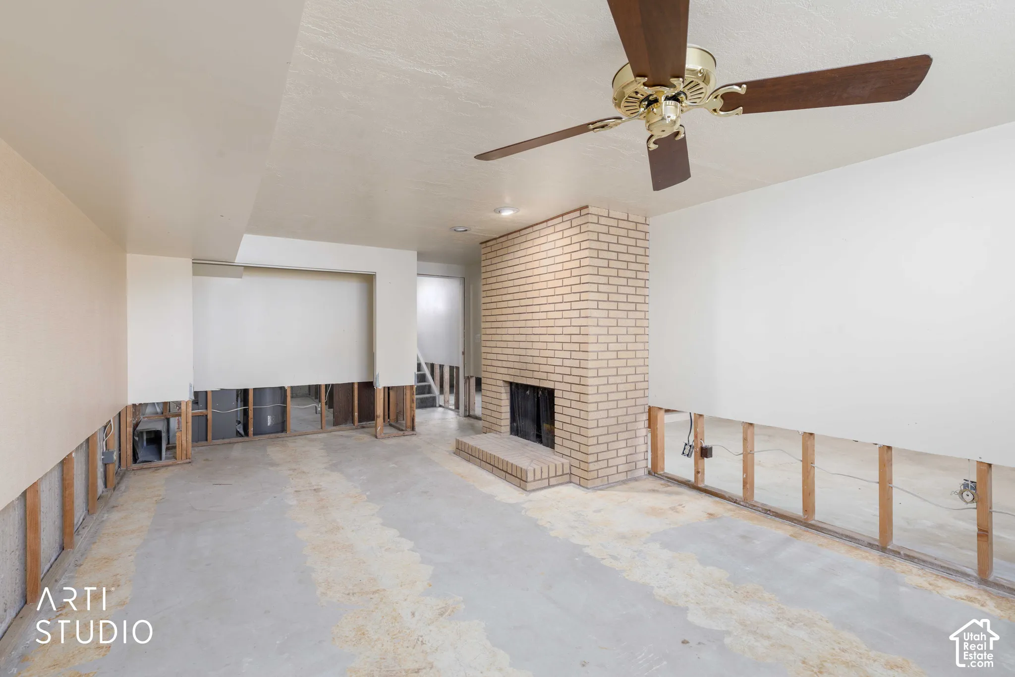 Full-height brick masonry fireplace with a raised hearth, ceiling-mounted paddle fan, and recessed lighting