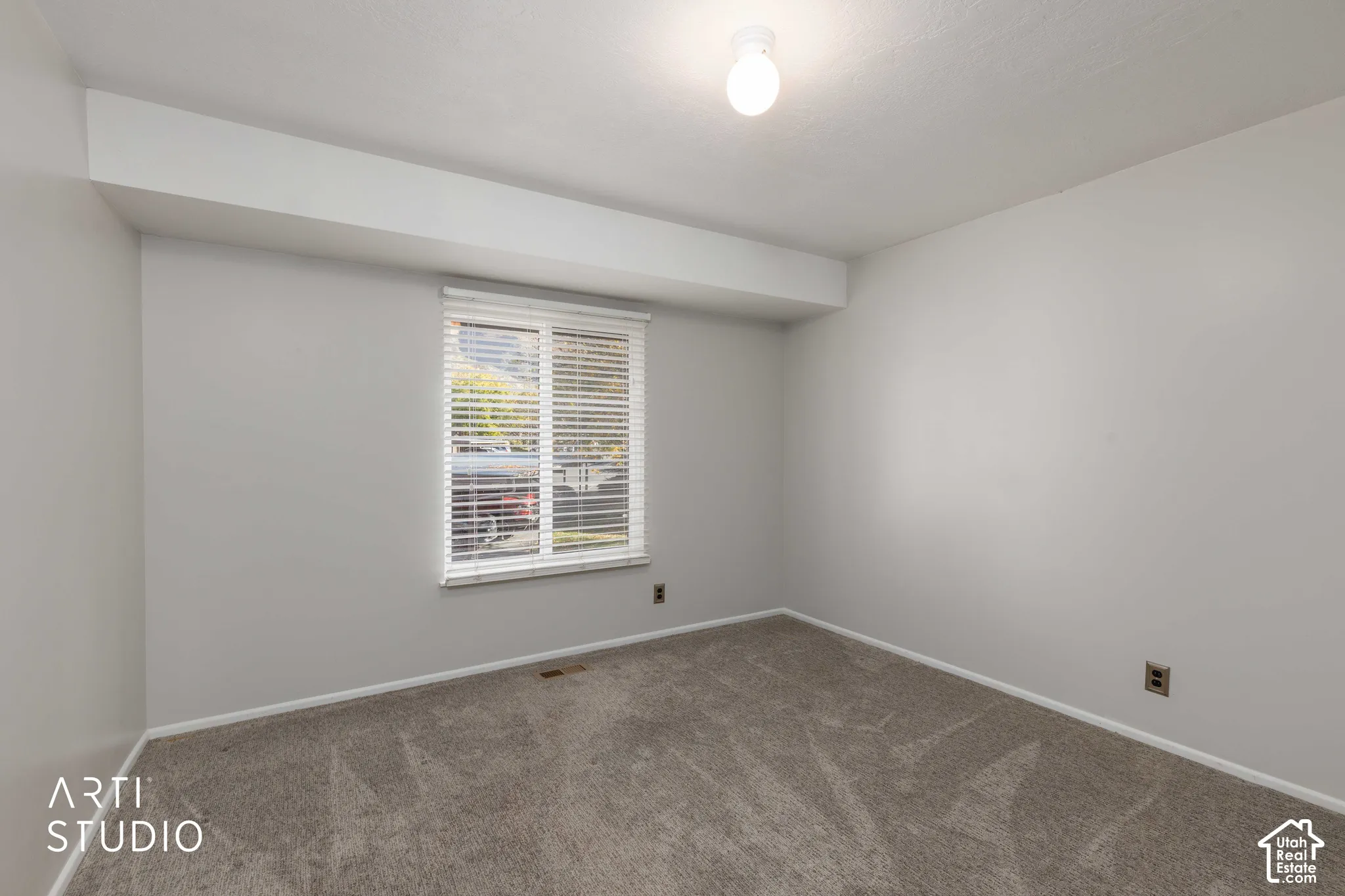 Neutral interior space featuring carpeted flooring, light-colored walls, and a window with horizontal blinds