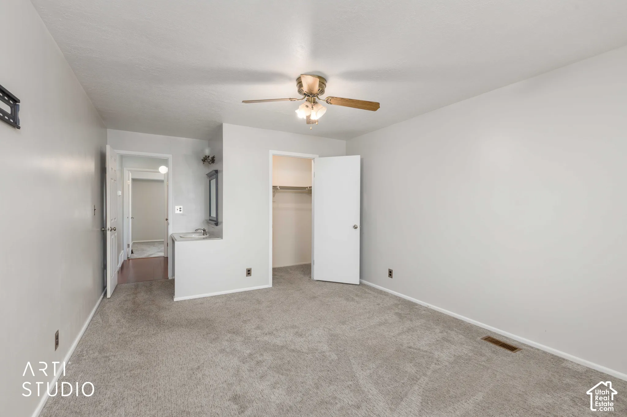 Neutral interior featuring wall-to-wall carpeting, an integrated vanity with a sink, a ceiling fan with integrated lighting, and a reach-in closet with built-in shelving