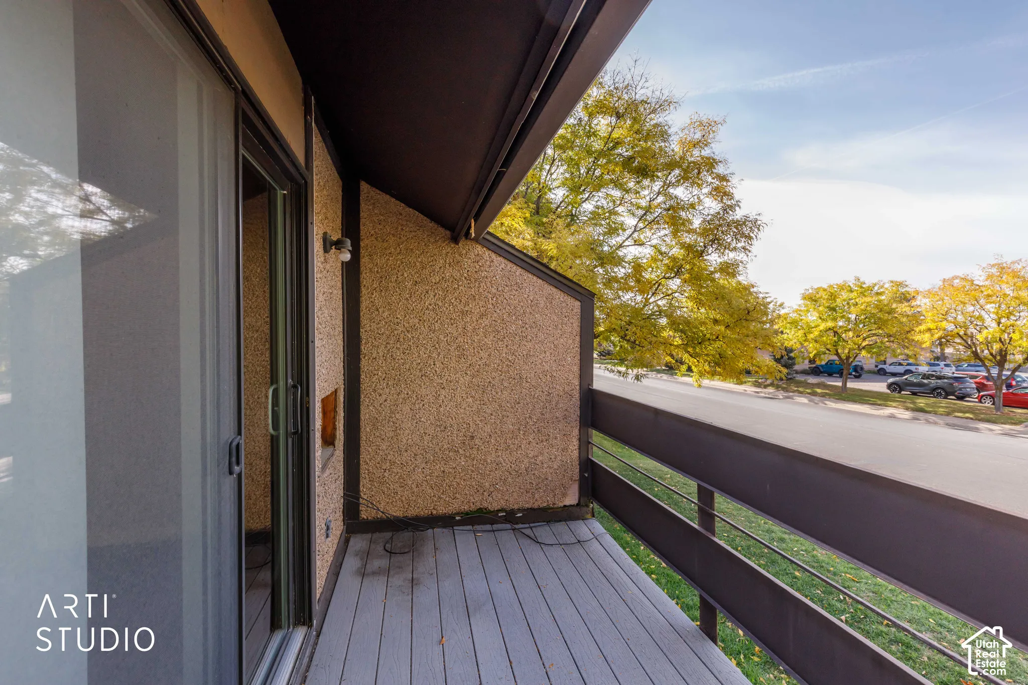 Private balcony featuring slate-toned decking, textured exterior siding, and a metal railing