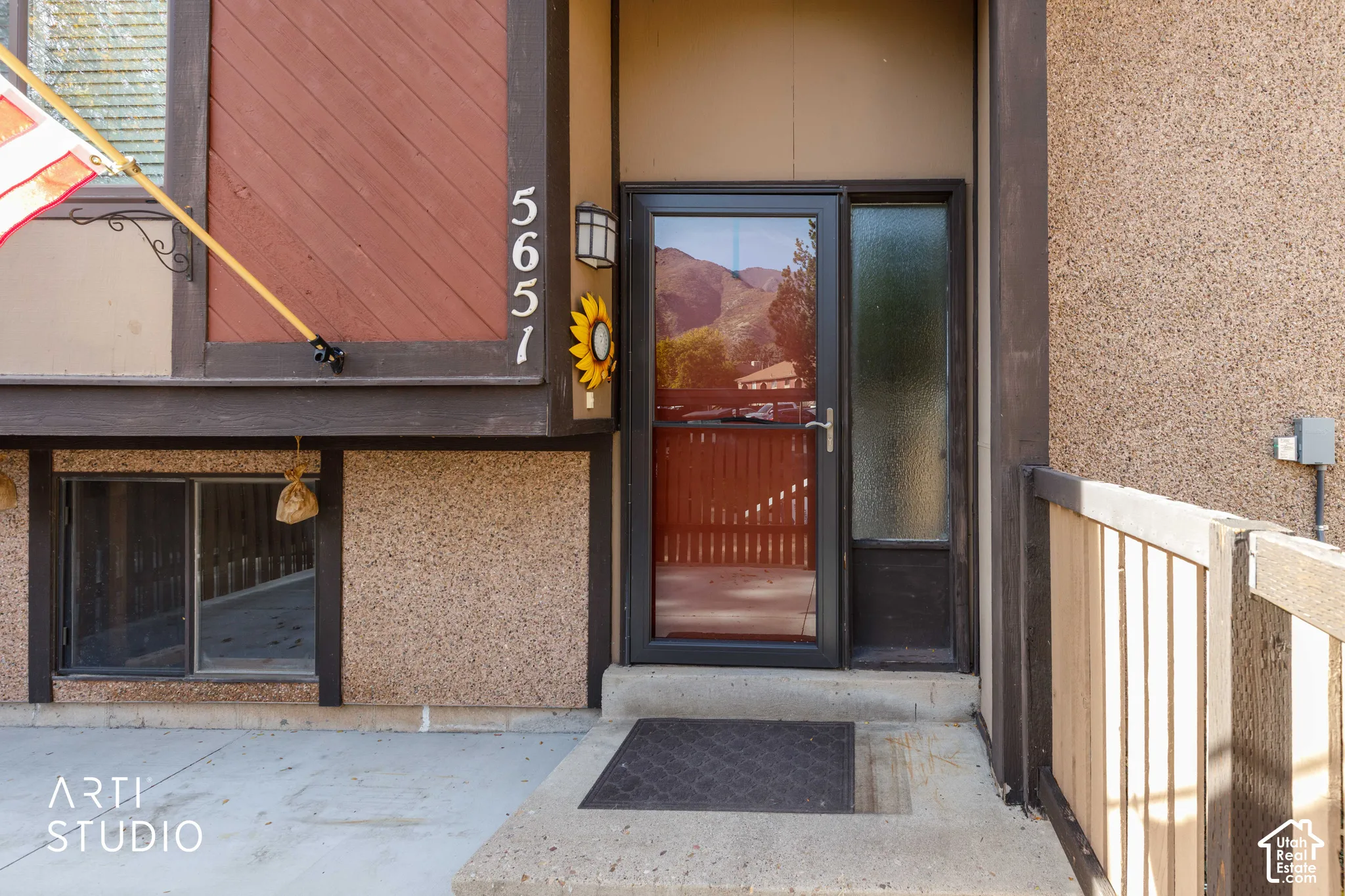 Exterior entry featuring a glass storm door with sidelight, textured stucco and wood siding, and concrete porch foundation