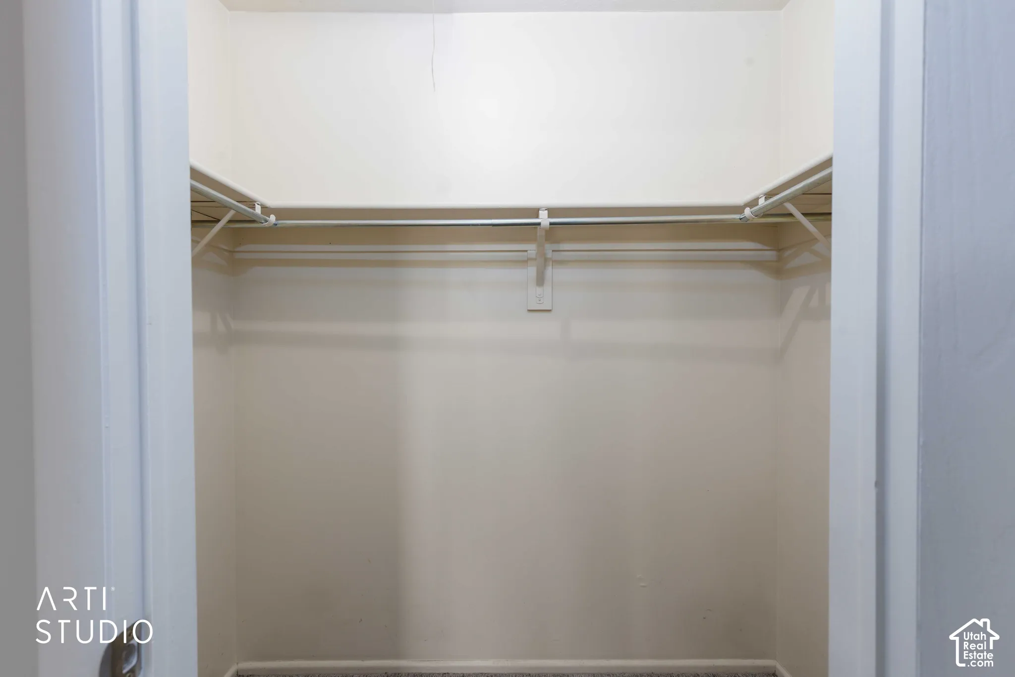 Closet featuring white shelving and a metal garment rod