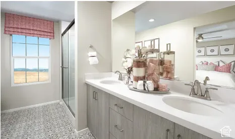 Bathroom featuring a dual-sink vanity with light wood-finish cabinetry, a large solid-surface countertop, full-width wall mirror, and a glass-enclosed shower