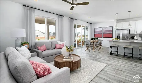 Open-concept interior featuring light wood-finish flooring, white cabinetry, a kitchen island with stone-style countertops, recessed ceiling lighting, and sliding glass doors