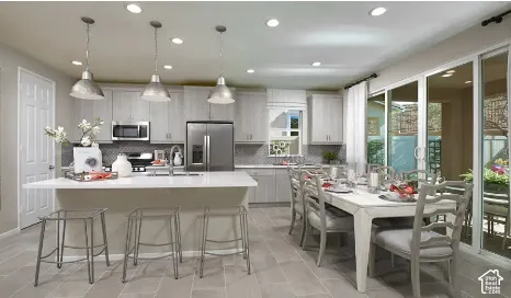 Kitchen featuring light-toned cabinetry, a quartz-topped center island with pendant lighting, stone-tiled backsplash, stainless steel appliances, and large sliding glass doors