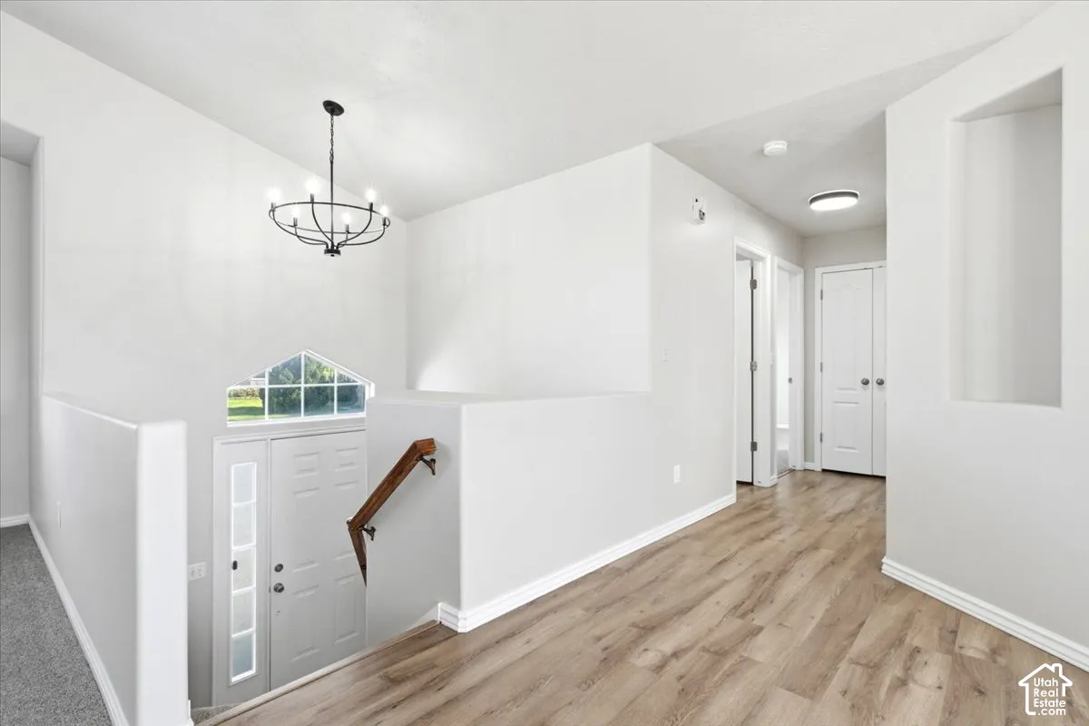 Interior space featuring wood-finish flooring, a multi-arm chandelier, an architectural wall niche, a wooden handrail, and an arched window