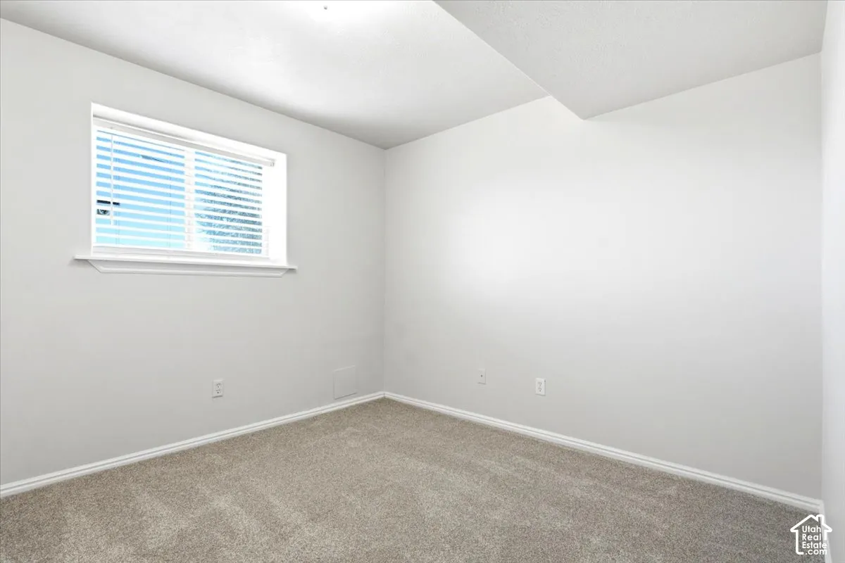 Interior space featuring neutral wall paint, wall-to-wall carpeting, and a recessed window with fitted blinds