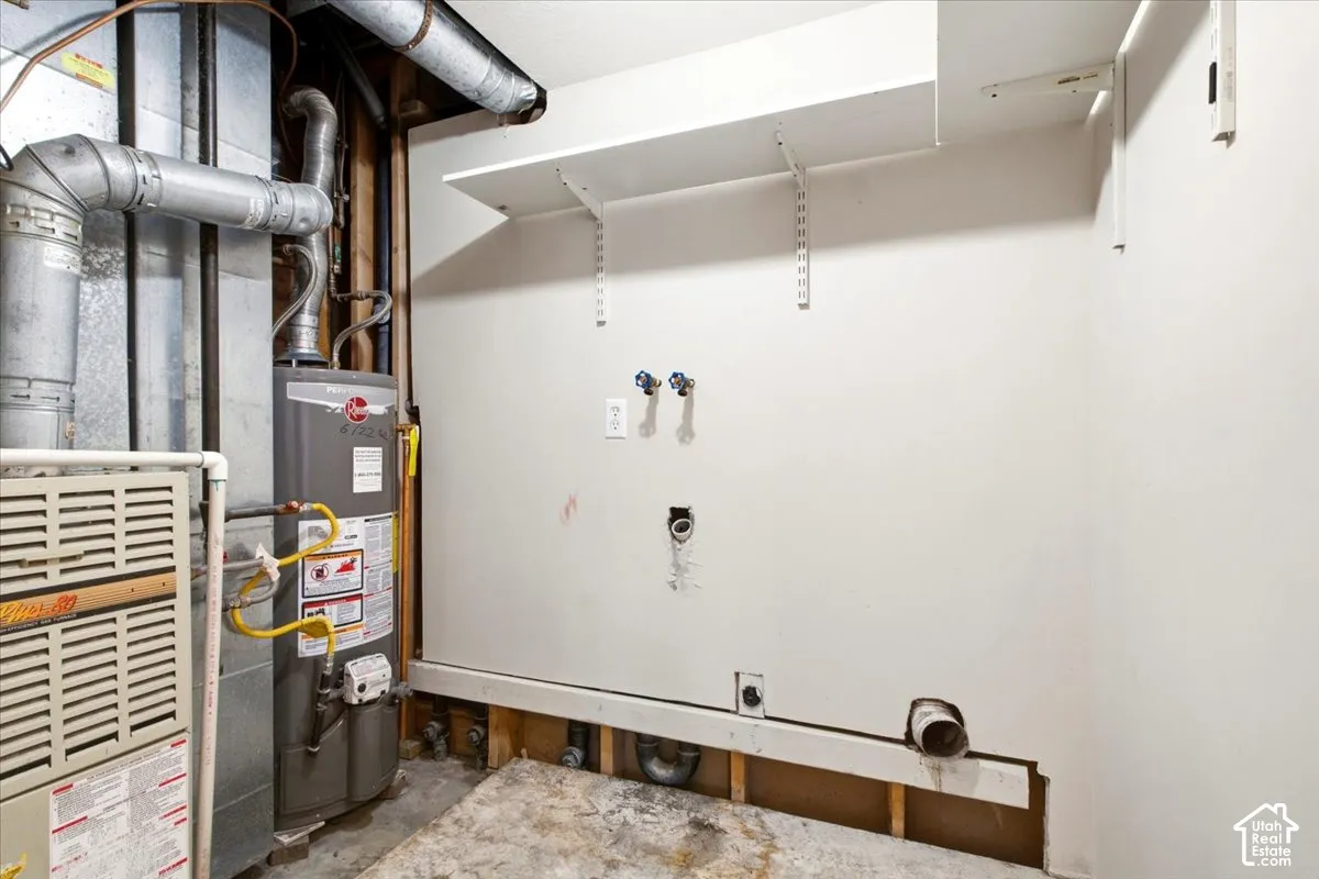 Utility area featuring a gas-fired water heater, forced-air furnace, and wall-mounted shelving units, including hookups for laundry appliances