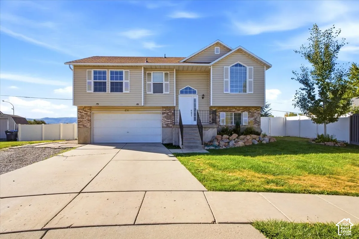Two-story exterior featuring vinyl siding, stone veneer accents, an attached two-car garage, concrete driveway, and arched decorative window