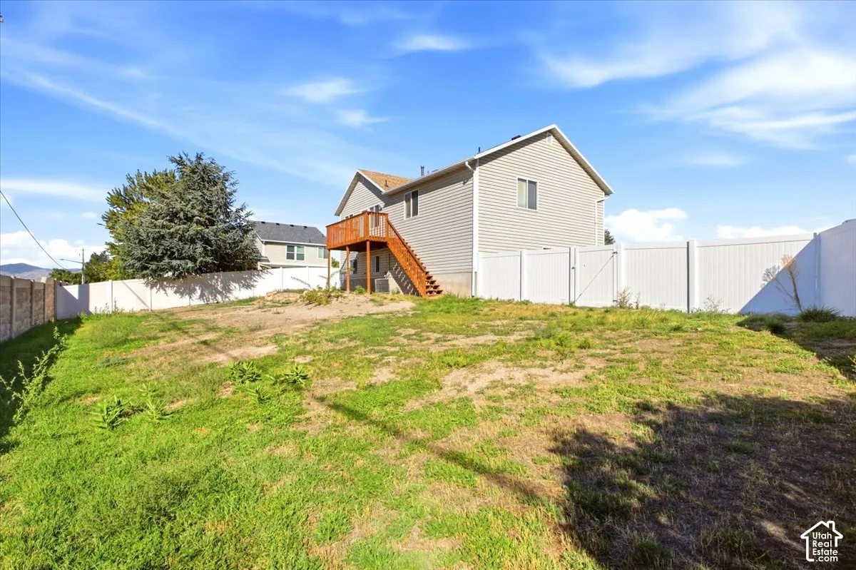 Fenced backyard featuring an elevated wood deck with exterior staircase and siding exterior