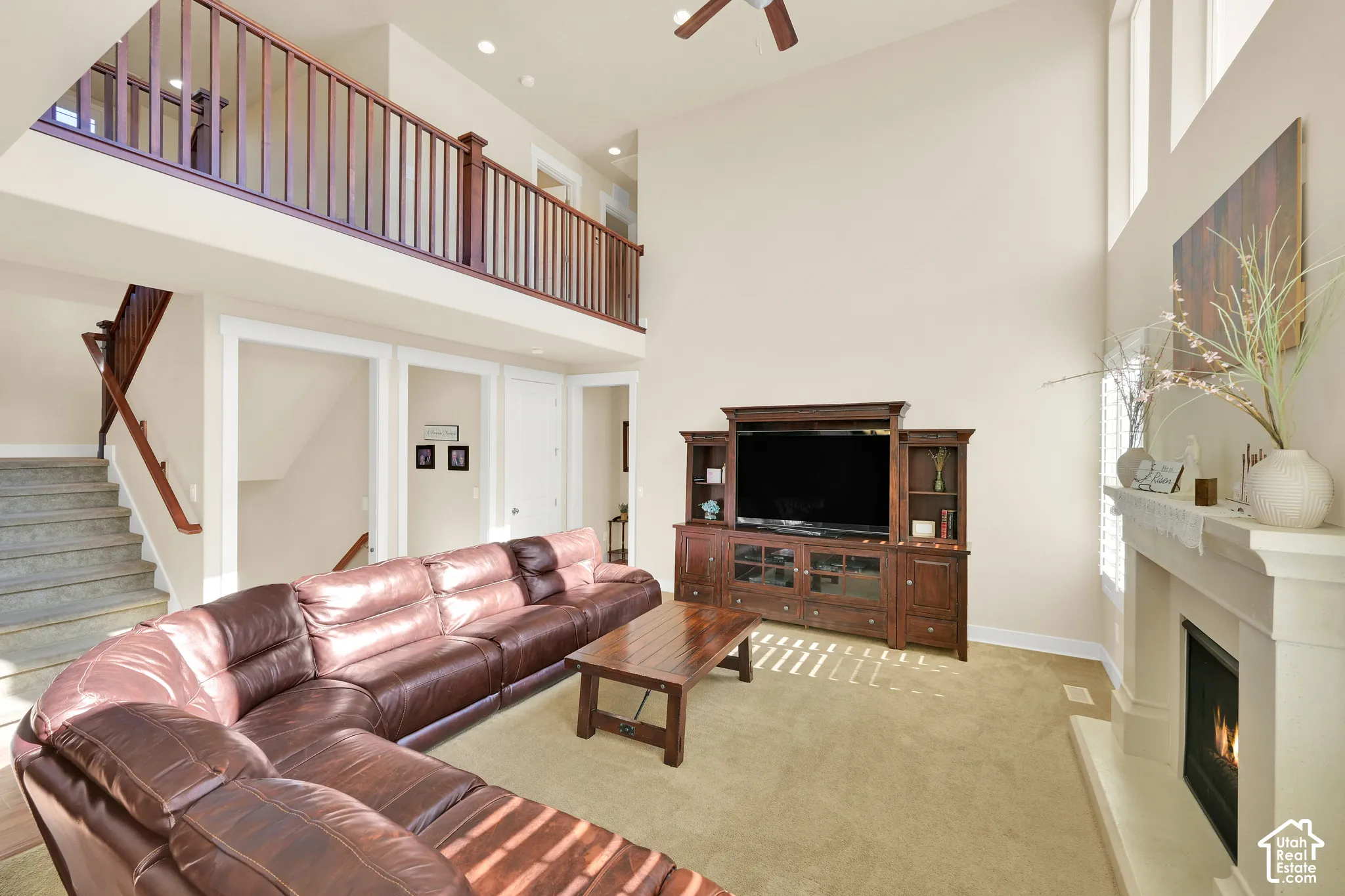 Double-height living area featuring a wood-rail mezzanine, fireplace with a decorative surround, and multi-level windows