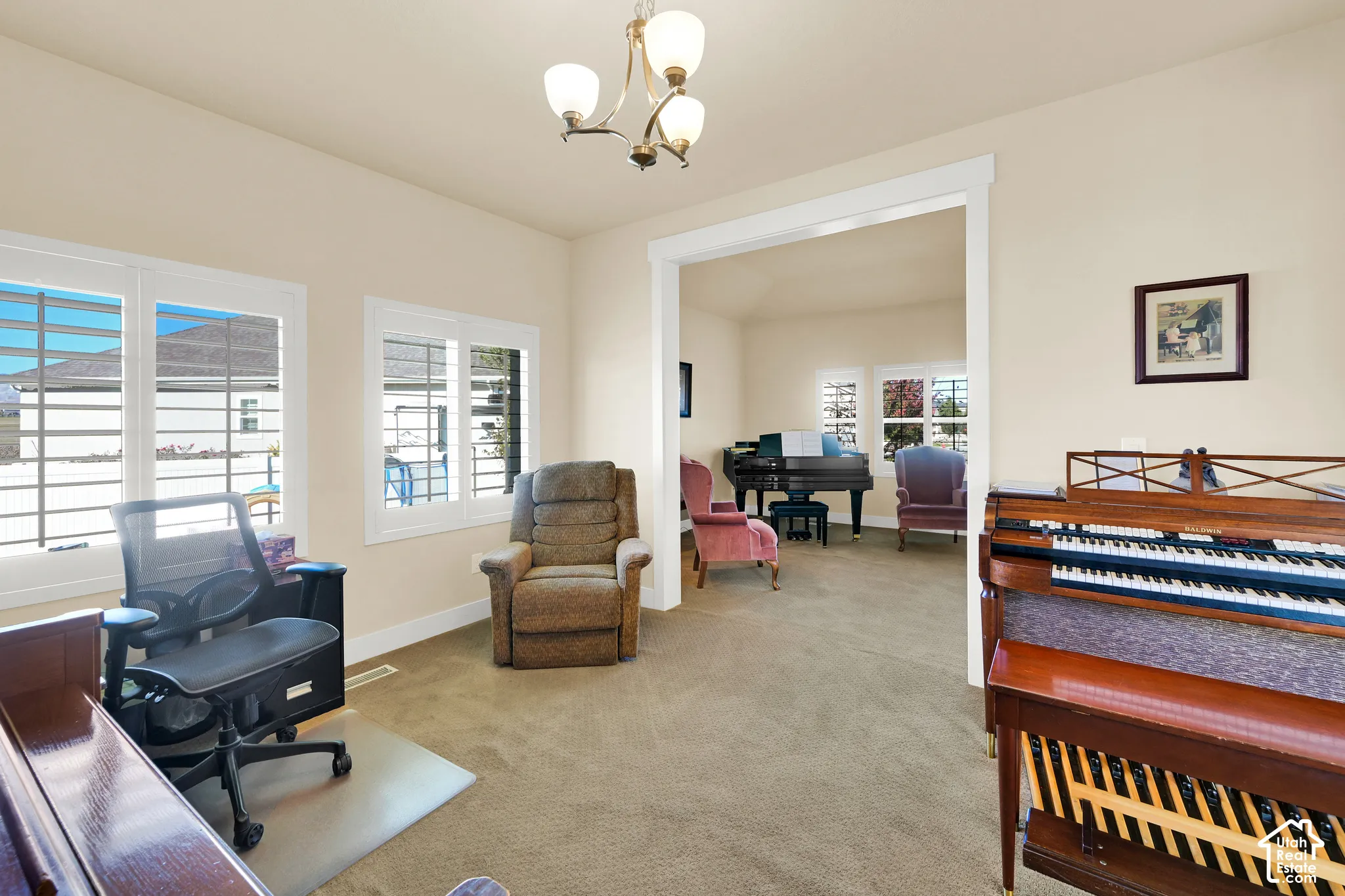 Neutral walls, multi-paned windows with integrated shutters, wall-to-wall carpeting, and a traditional multi-arm chandelier