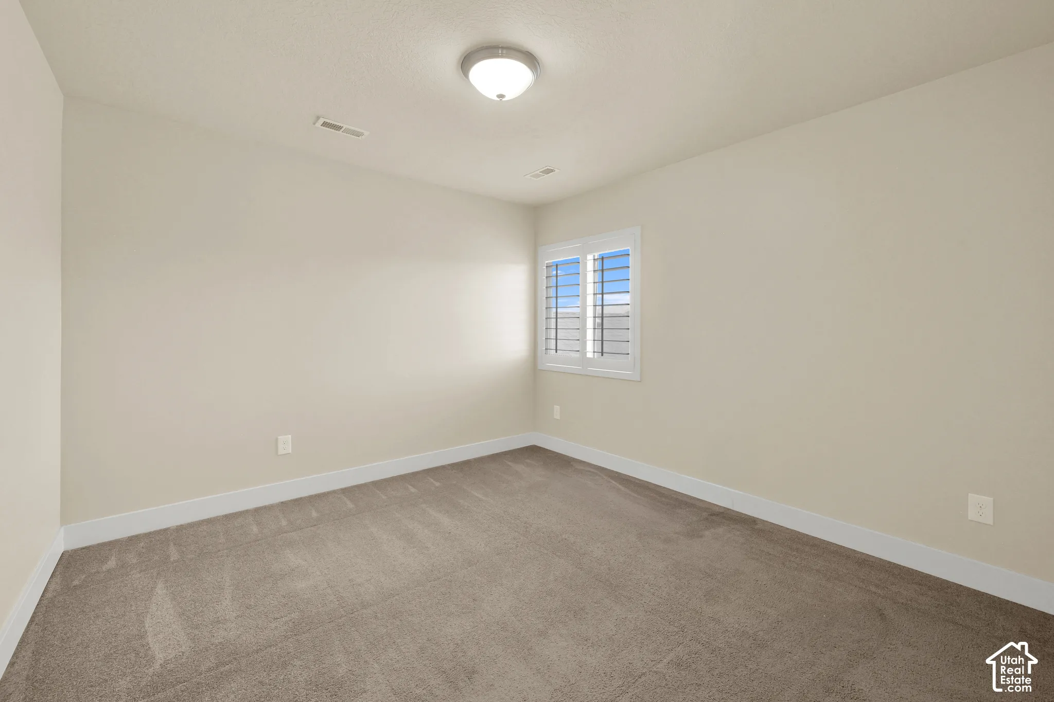 Neutral-toned interior space featuring neutral wall paint, carpeting, and plantation-style window shutters