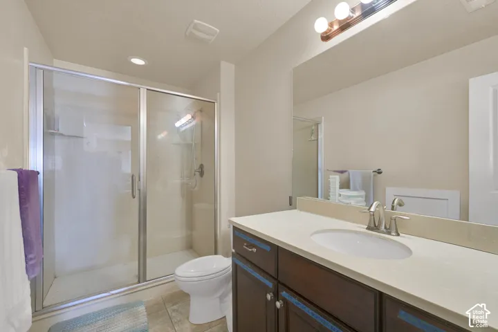 Bathroom featuring a vanity with a neutral solid-surface countertop, an undermount sink, a large wall-mounted mirror, a walk-in shower with a glass enclosure, and recessed lighting