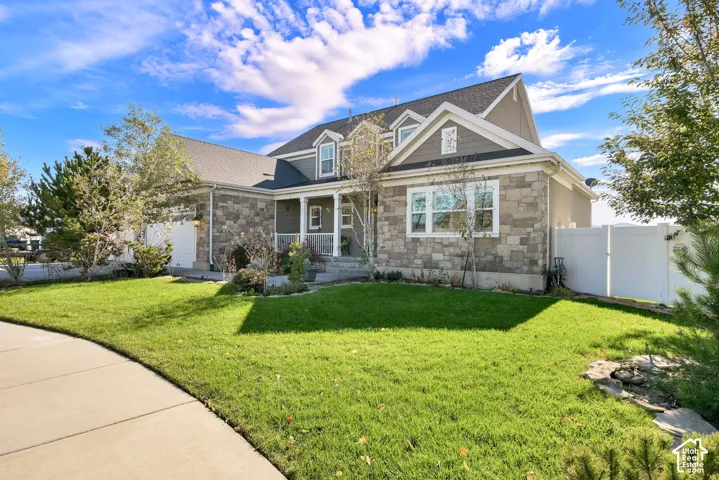 Two-story exterior featuring multi-gabled rooflines, stone masonry facade, horizontal siding, and a concrete driveway