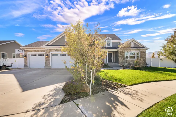 Multi-level residence featuring a stone and siding exterior, two-car garage, and concrete driveway