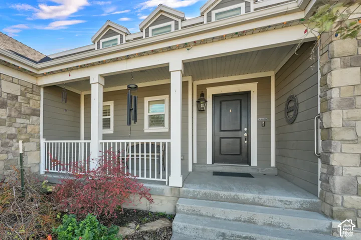Covered front porch featuring stacked stone accents, horizontal lap siding, white wooden railings, and three roof dormers