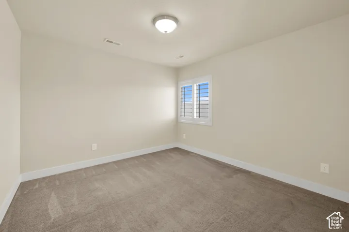 Neutral-toned interior space featuring neutral wall paint, carpeting, and plantation-style window shutters