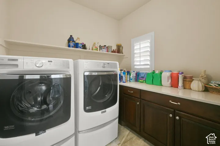 Laundry area featuring dark wood-finish cabinetry, a neutral solid-surface countertop, an elevated built-in storage shelf, and a shuttered window