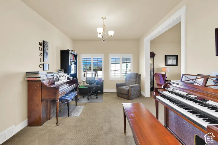 Room featuring neutral wall tones, wall-to-wall carpeting, dual windows with interior plantation shutters, and a central multi-arm light fixture