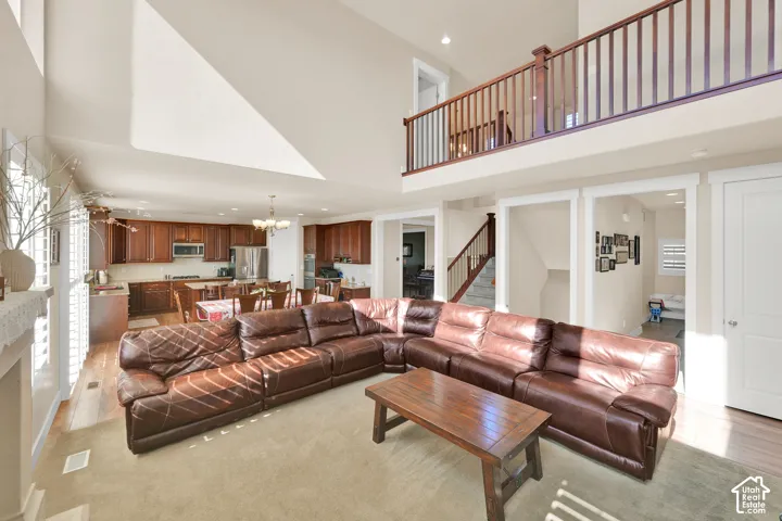 Open-concept floor plan featuring soaring vaulted ceilings, a mezzanine balcony with wood-railing balusters, and a kitchen equipped with built-in cabinetry and stainless steel appliances