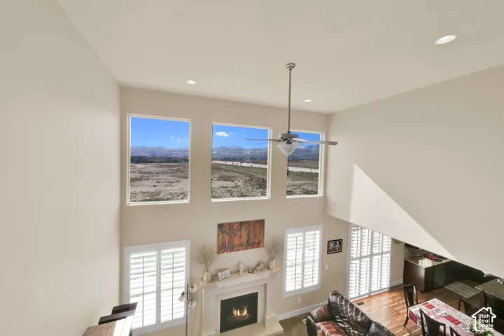 Vaulted ceilings, expansive windows with mountain scenery, white plantation shutters, and a fireplace with a custom mantel