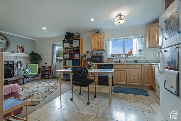 Kitchen featuring natural wood cabinetry, stone-finish tile flooring, a dual-basin sink, and a masonry fireplace