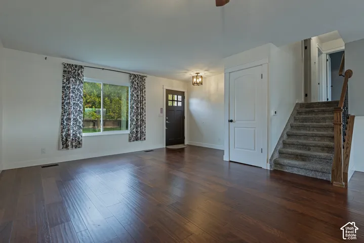 Wood-finish flooring, multi-light front entry door, semi-flush mount lighting, and staircase with carpeted treads and wooden railing