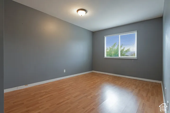Neutral grey wall paint, wood-finish flooring, sliding window with horizontal blinds, and a flush-mount overhead light fixture