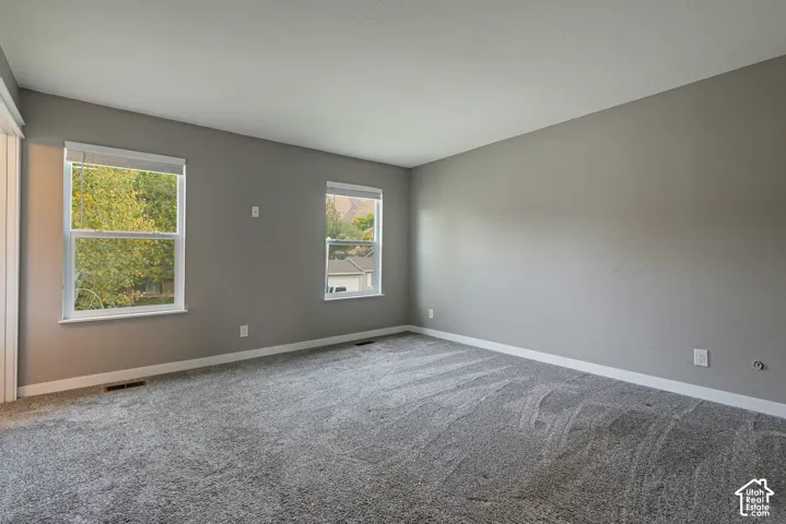 Neutral-toned interior space featuring neutral wall paint, wall-to-wall carpeting, and double-pane windows with integrated blinds