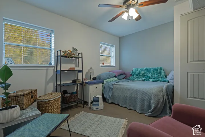 Room featuring dual windows, neutral wall paint, a ceiling fan with integrated lighting, and a two-panel interior door