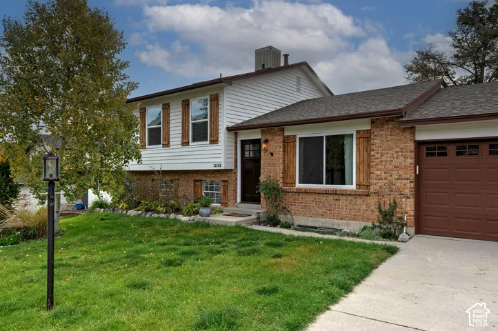 Exterior featuring a combination of brick and horizontal siding, wood-finish shutters, an attached garage, and concrete driveway