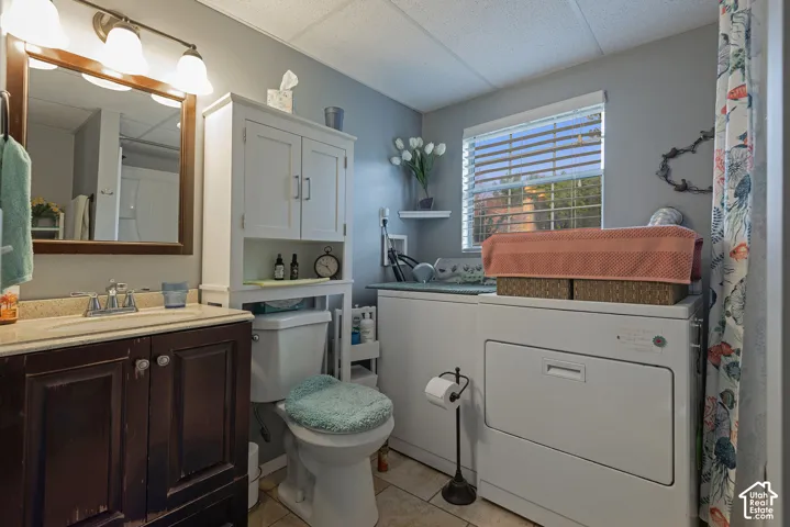 Dark wood vanity with a stone countertop, integrated sink, and polished chrome faucet, featuring a wall-mounted wood-frame mirror with a three-light fixture, built-in over-the-toilet cabinetry, and tile flooring