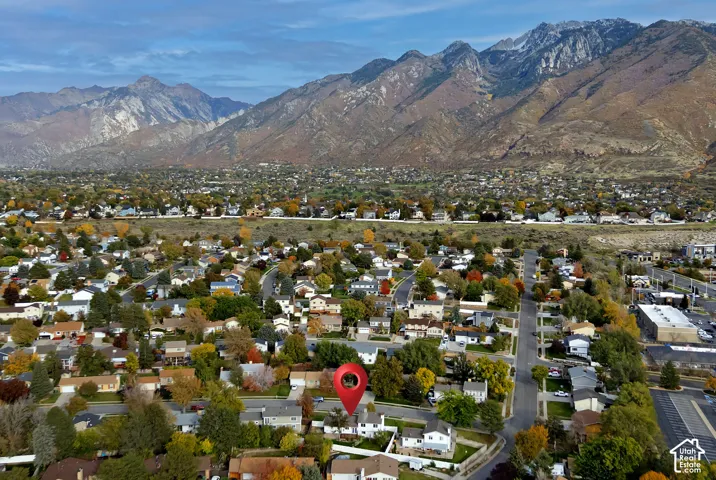 Aerial perspective showcasing a residential property situated against a prominent mountain backdrop with mature trees and established landscaping