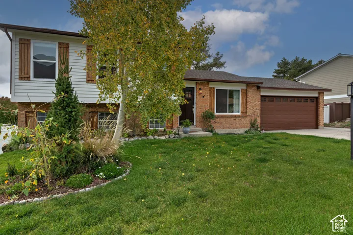 Multi-level exterior featuring a combination of brick and horizontal siding, decorative wood shutters, and an attached two-car garage
