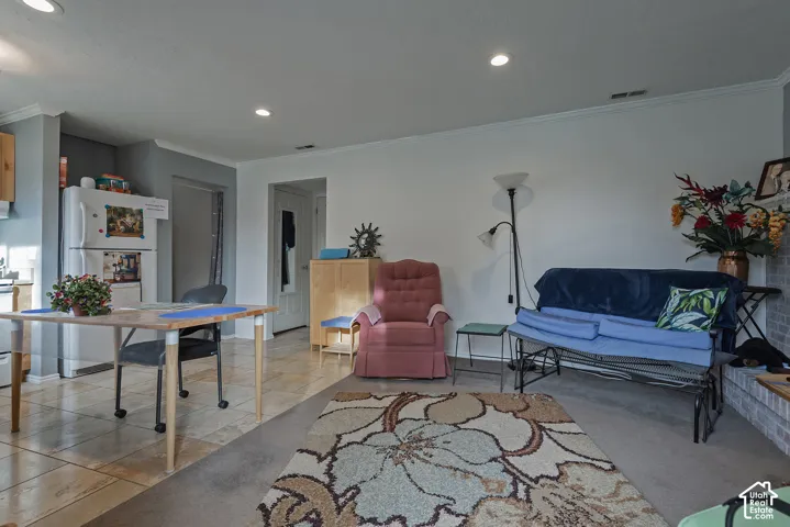Open-concept living space featuring recessed lighting, neutral wall paint, tile flooring, and a brick fireplace surround