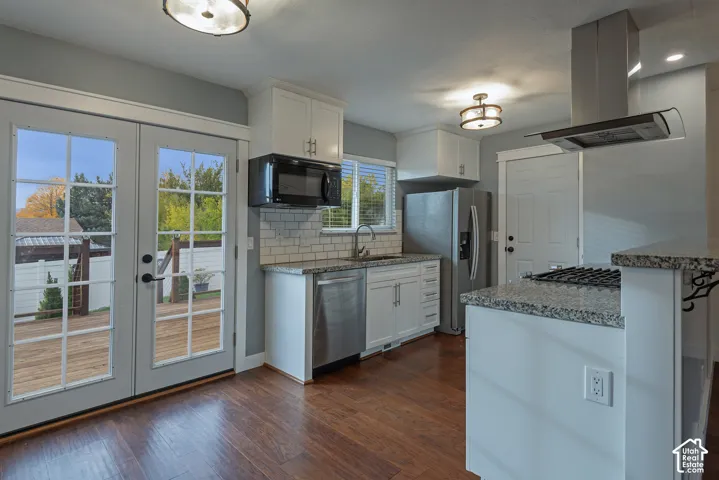 Kitchen featuring white shaker-style cabinetry, stone countertops, stainless steel appliances, white subway tile backsplash, and wood-finish flooring