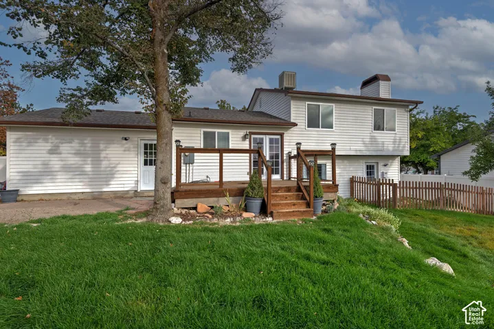 Backyard featuring a wood deck with railing, sliding glass doors, horizontal siding, and perimeter fencing