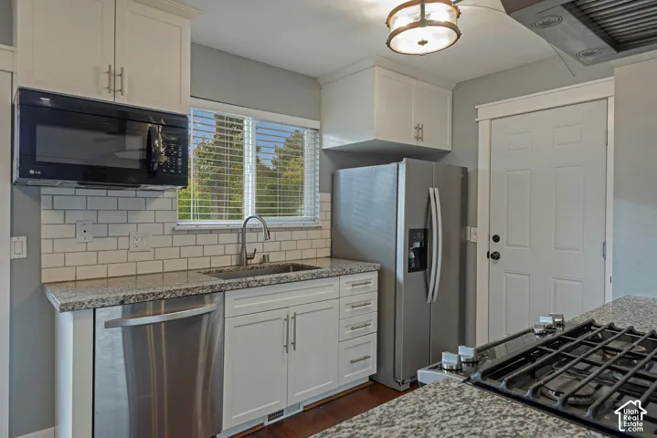 Kitchen featuring white shaker-style cabinetry, stone-patterned countertops, a white subway tile backsplash, stainless steel appliances, and a gas cooktop