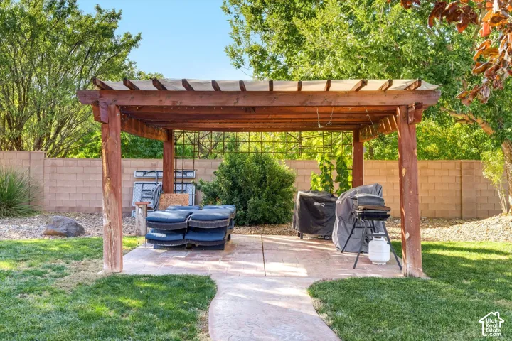 Outdoor wooden pergola featuring a stamped concrete patio, trellis back wall, and surrounding manicured lawn