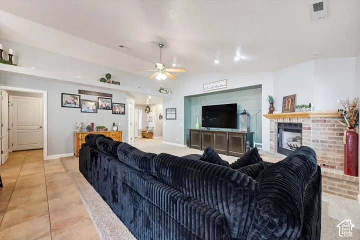 Vaulted ceilings, brick-surround fireplace with a wooden mantel, recessed display niche, and tile flooring