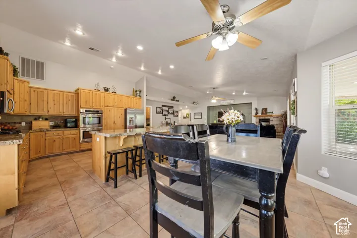 Open-concept interior featuring vaulted ceilings, recessed lighting, natural wood-finish cabinetry, built-in double wall ovens, and tile flooring