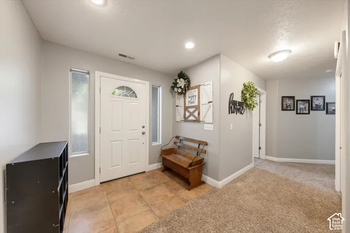 Entryway featuring neutral-toned wall paint, ceramic tile flooring, flush-mount lighting, recessed lighting, and vertical sidelight windows flanking the front door