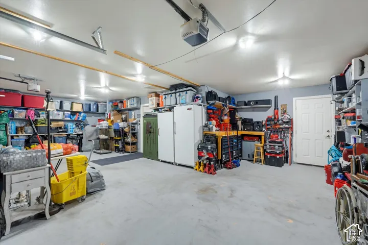 Expansive garage featuring a high-clearance ceiling, durable concrete flooring, overhead fluorescent lighting, and a dedicated entry door