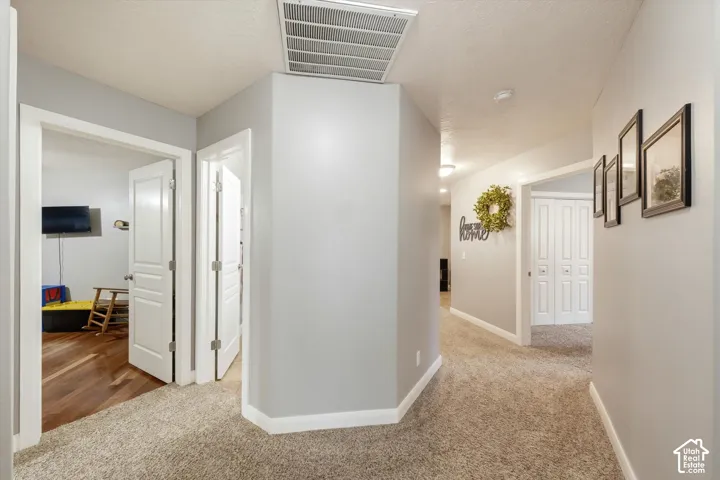 Hallway featuring neutral wall paint, multi-panel interior doors, and wall-to-wall carpeting