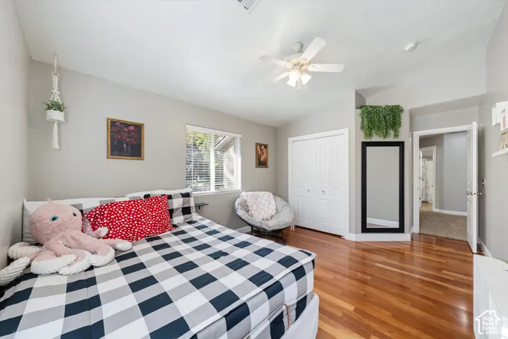 Room featuring wood-finish flooring, a vaulted ceiling with a central ceiling fan, and a double-door closet