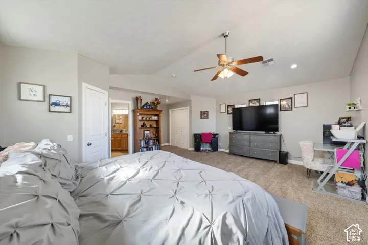 Spacious room featuring a vaulted ceiling, ceiling fan with light fixture, neutral wall color, and wall-to-wall carpeting