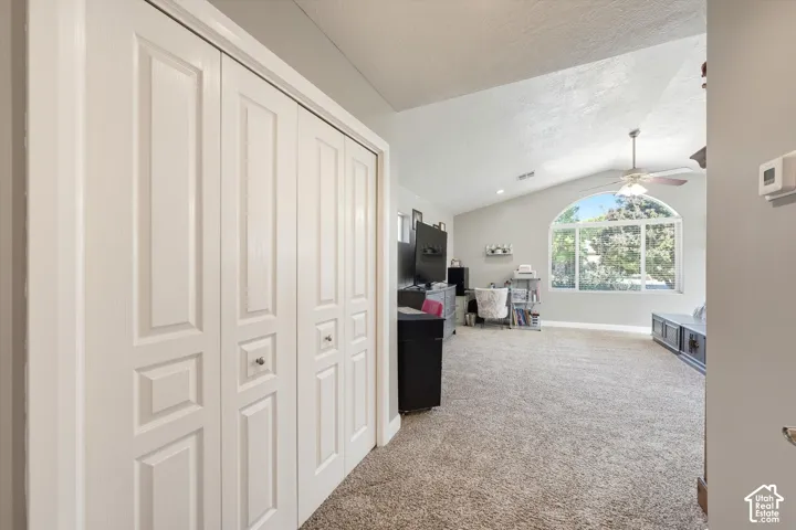 Interior space featuring vaulted ceilings, arched window, wall-to-wall carpeting, and floor-to-ceiling bifold closet doors
