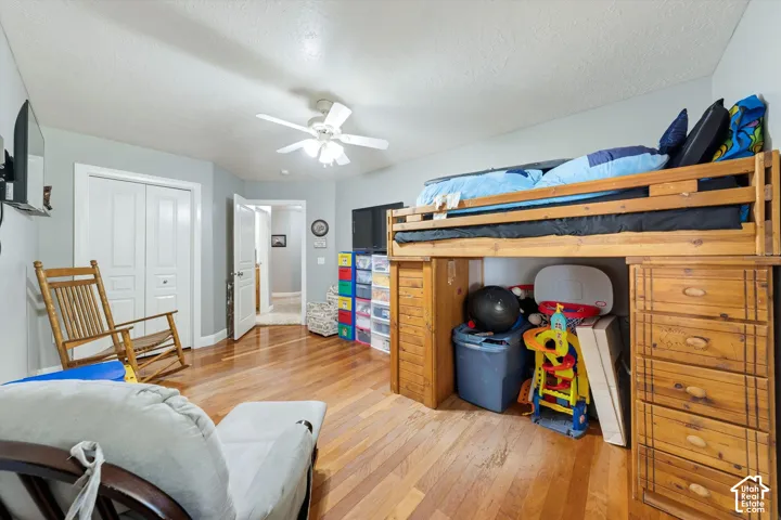 Wood-finish flooring, white double-door closet, and white ceiling fan with integrated lighting