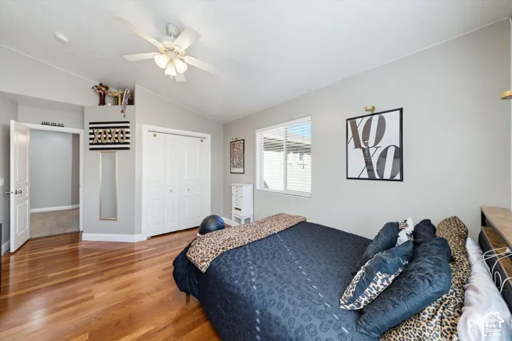 Room with vaulted ceilings, wood-finish flooring, white bifold closet doors, and a ceiling fan with integrated lighting